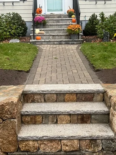 Outdoor stone steps leading to a house entrance, decorated with pumpkins and flowers for Halloween